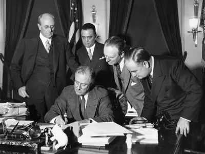 J. Edgar Hoover (second from left) stands behind Franklin Delano Roosevelt as the president signs a bill in 1934.