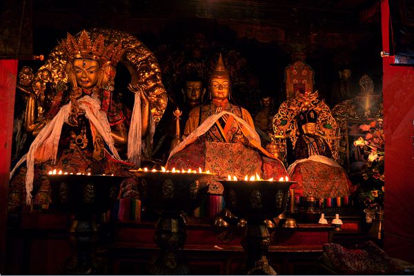 Statues of different Buddahs at the Deprong Monastery, lit with yak butter lamps and wearing the white silk khatas thumbnail