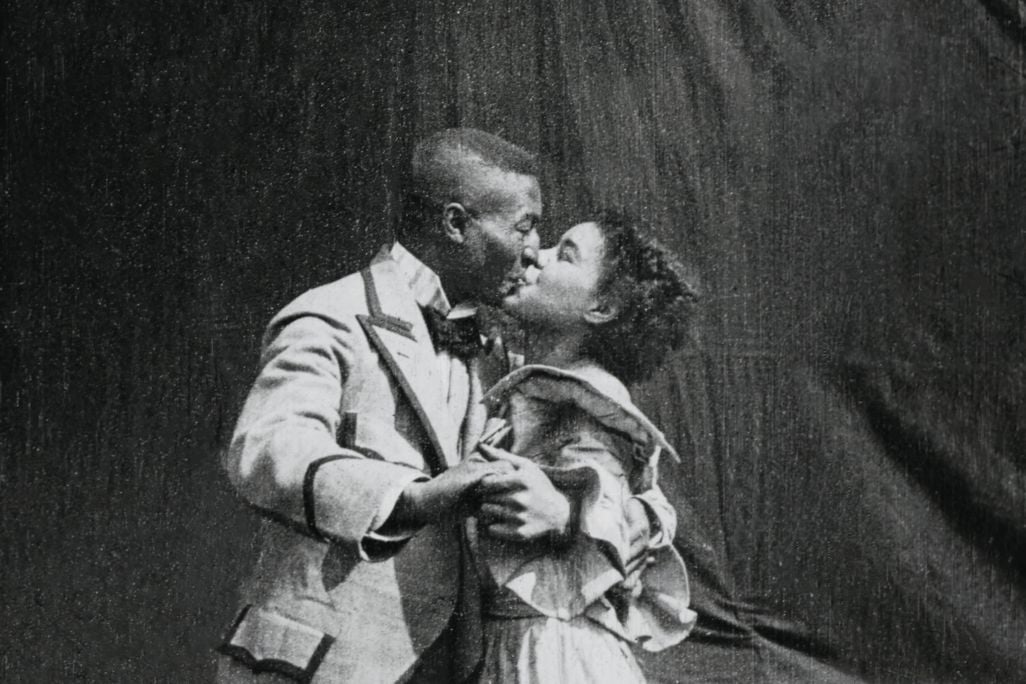 Black and white image of a black man and a black woman kissing