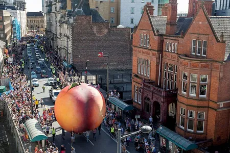 People gathered to watch a giant peach as it is moved through the center of Cardiff in September 2016—part of a celebration of the 100th anniversary of Roald Dahl's birth.