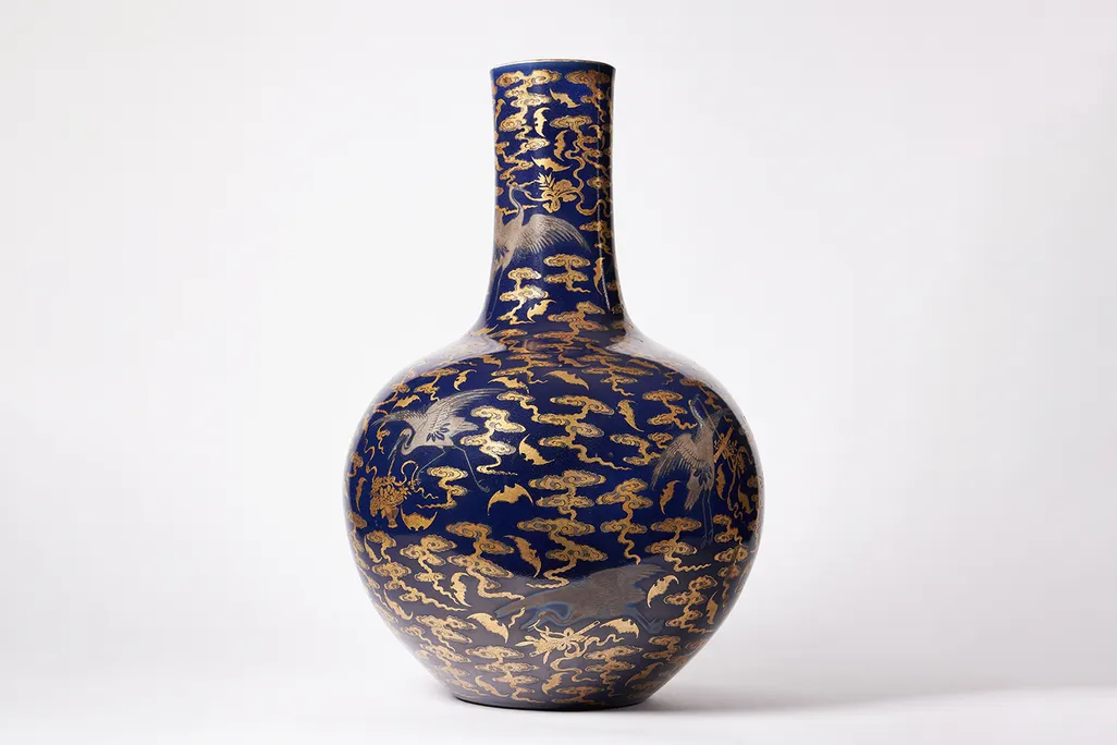 Picture of a blue and gold vase with a round body and thin neck