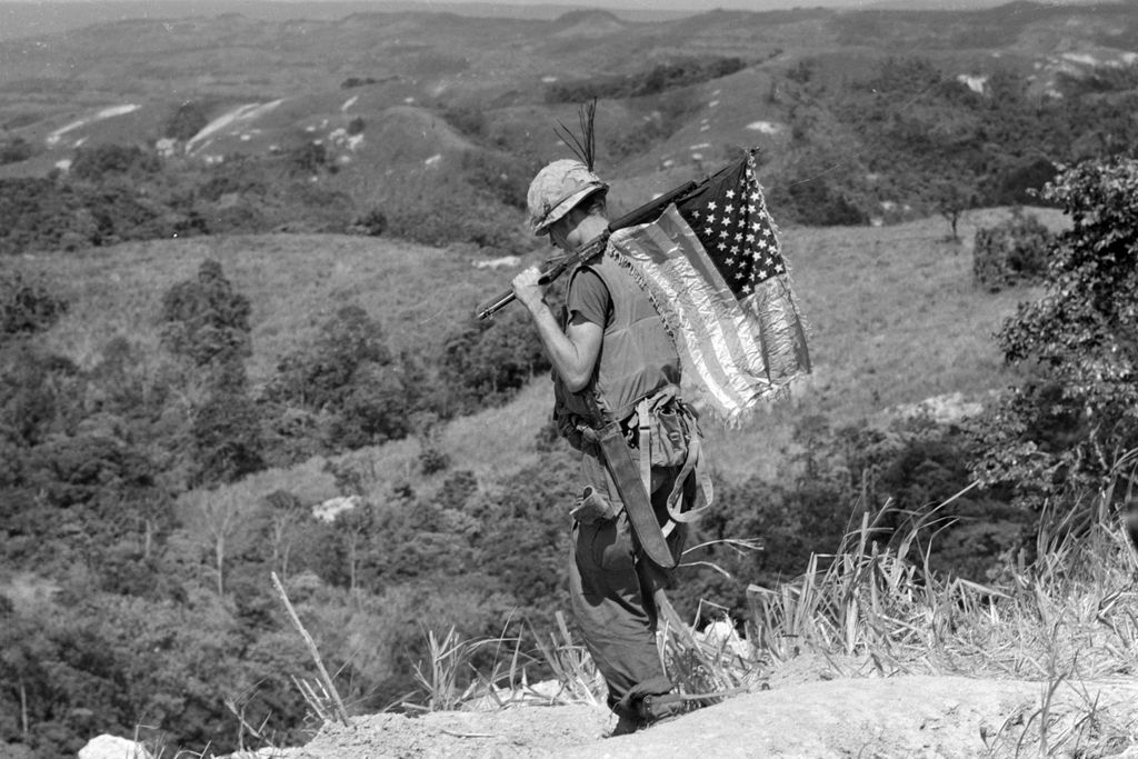 A U.S. Marine carries an American flag on his rifle during a recovery operation