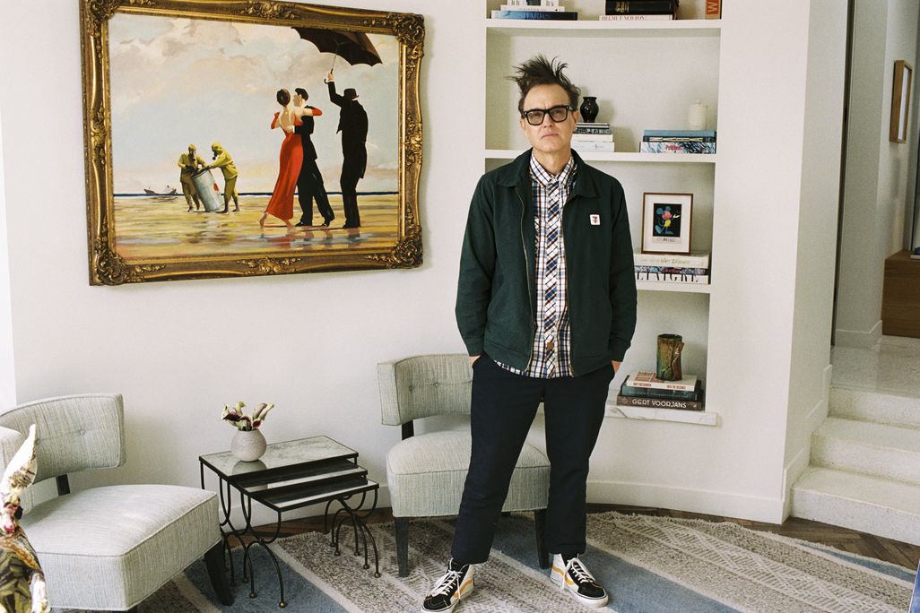 A man wearing glasses standing in front of a painting