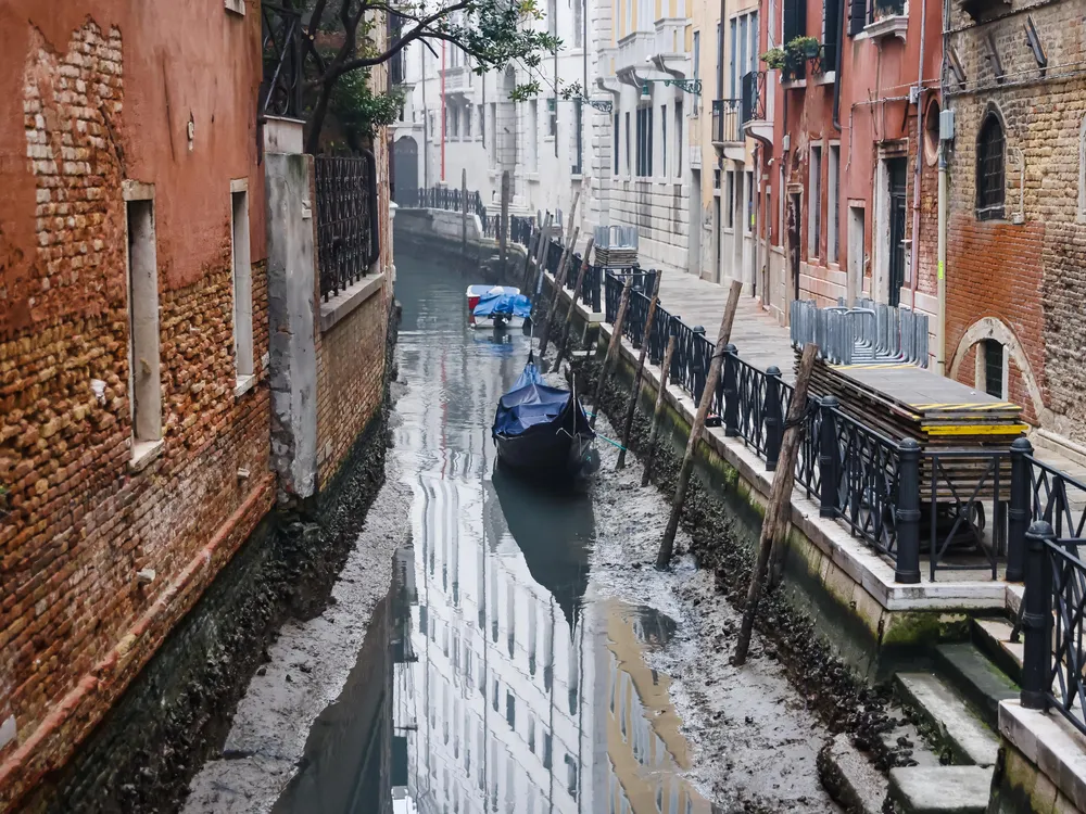 Boats in muddy canal with little water in Venice