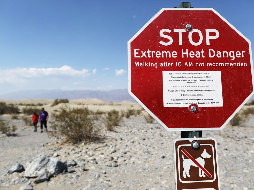 A stop sign in Death Valley reads "Extreme Heat Danger; Walking after 10 AM not recommended"