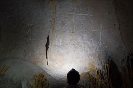 A researcher examines inscriptions by 16th century Europeans in a cave on Mona Island