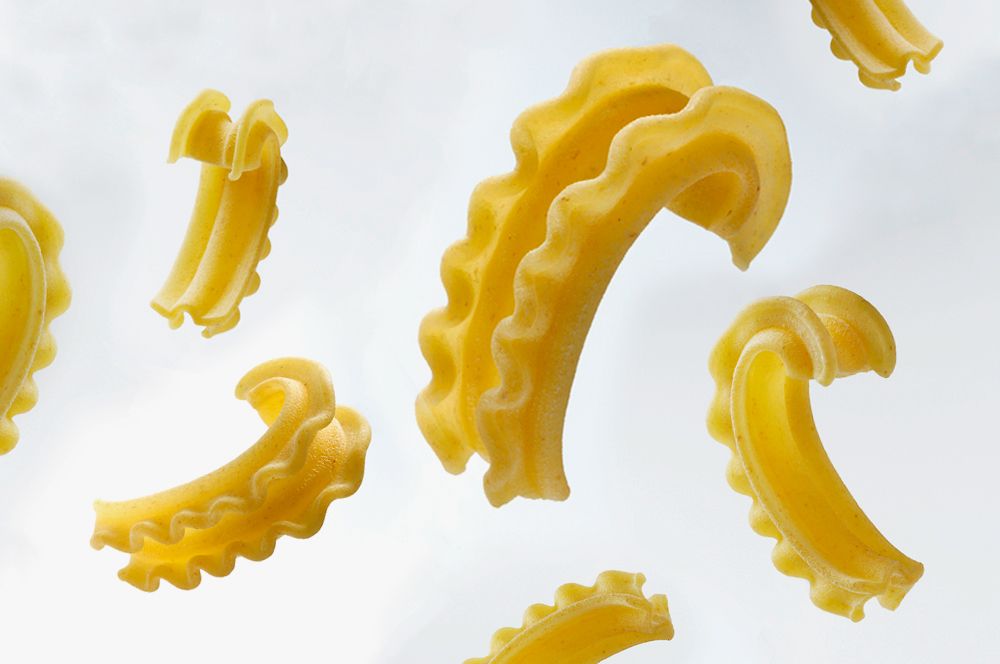 A photo of various Cascatelli pasta falling against a white background 