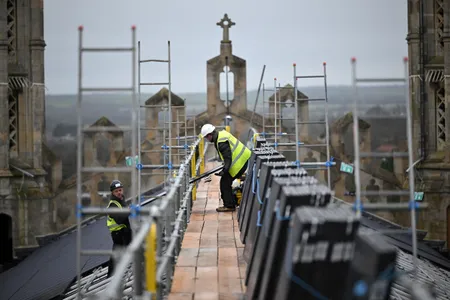 Workers install solar panels on the roof of King&#39;s College Chapel in Cambridge, England.
