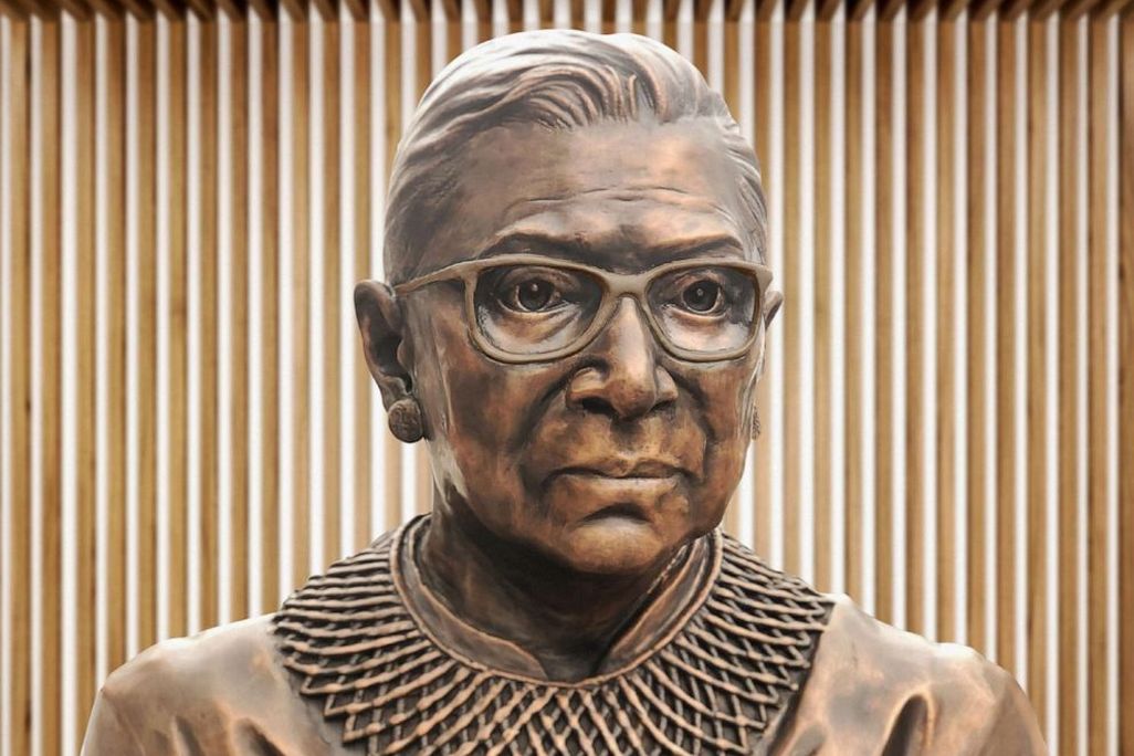 A close up of the bronze sculpture of RBG's face, with her distinctive collar and square glasses