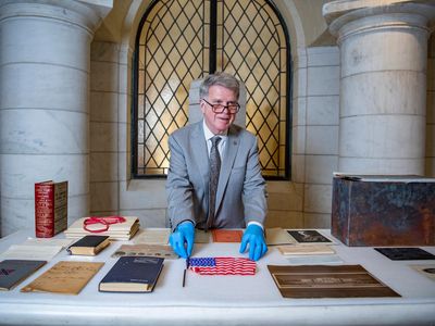 Archivist of the United States David S. Ferriero displays historical objects recovered from the Arlington National Cemetery time capsule. 