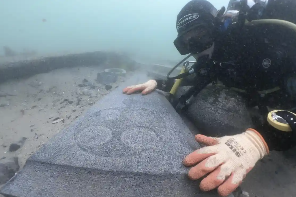 A marine archaeologist examines one of the engraved Purbeck gravestones recovered from the 13th-century Mortar Wreck