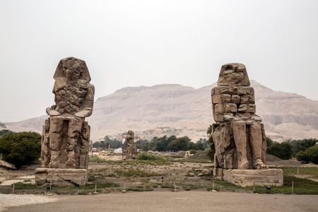 Statue of Memnon in the westbank in Luxor, with the community of Qurna in the background.