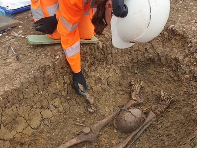 An archaeologist examines a beheaded body found at an ancient Roman cemetery in England.