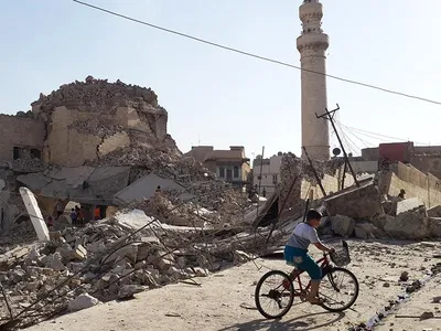 A bicyclist rides by the destroyed old mosque and tomb of  Nabi Jerjis, also known as Saint George, in central Mosul in July 2014.