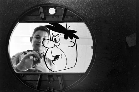 An unidentified Hanna-Barbera Productions painter works on an animation cel of Fred Flintstone. THE FLINTSTONES and all related characters and elements © & ™ Hanna-Barbera. (s16)