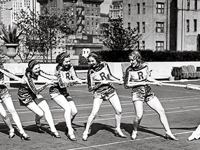Charles Atlas playing tug of war with the Rockettes atop Radio City Music Hall