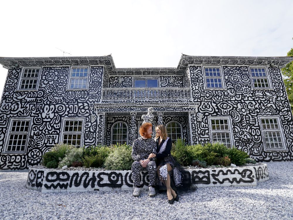 British artist Sam Cox, aka Mr Doodle, with his wife Alena, sitting before the Doodle House.