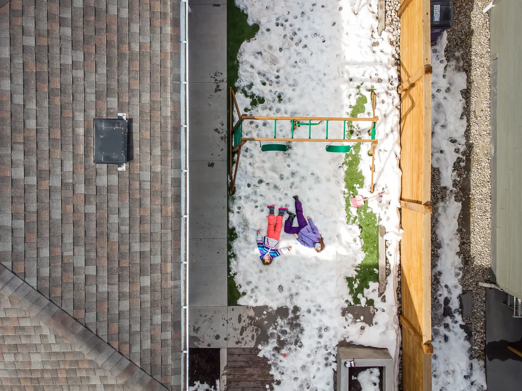 9 - With the sun beaming down and threatening their withering winter wonderland, children cling to what little snow is left in the yard of a home in Denver.