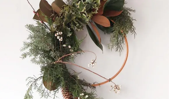 A modern evergreen wreath on a metal hoop displayed on a white background