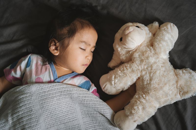 A child sleeping with a stuffed animal