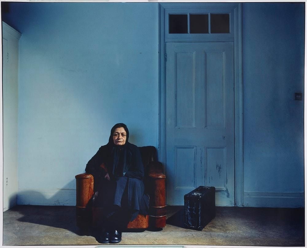 Seated woman with suitcase by door