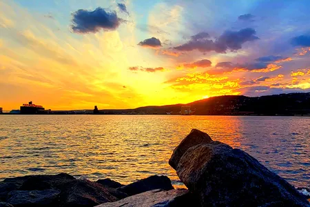 The sun sets behind the hills of Duluth, Minnesota, creating a warm glow on the shimmering surface of Lake Superior.