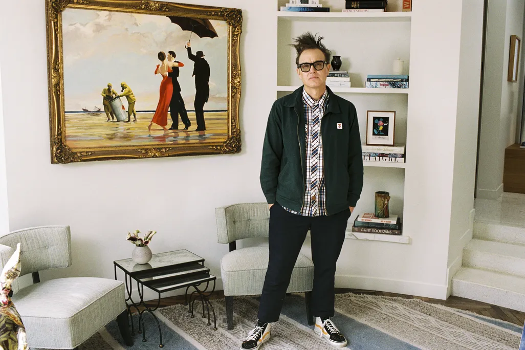 A man wearing glasses standing in front of a painting