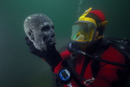 A diver holds a granite head, meant to be the head of a priest, from the Ptolemaic period. The now-hollow eyes were probably inlaid when it was first made in ancient Egypt.