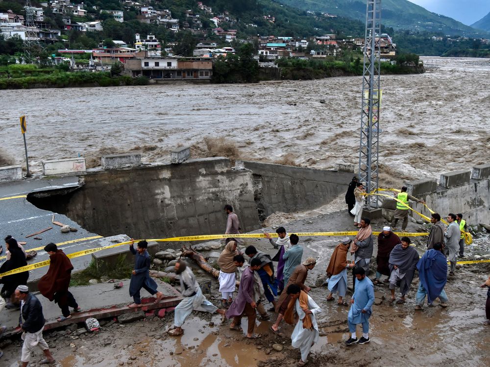 People surrounding a street damaged by flooding