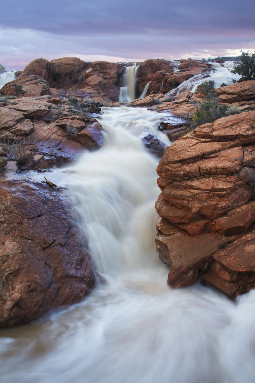 Rushing white water flowing down red rocks
