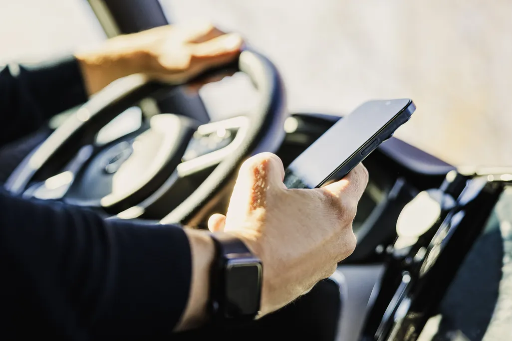 close-up of a hand holding a phone while the person is driving
