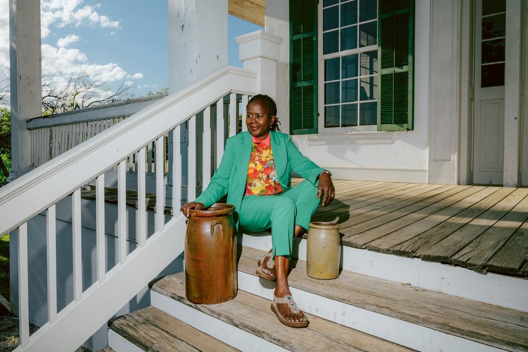 a woman in a green suite sits on a staircase next to pottery
