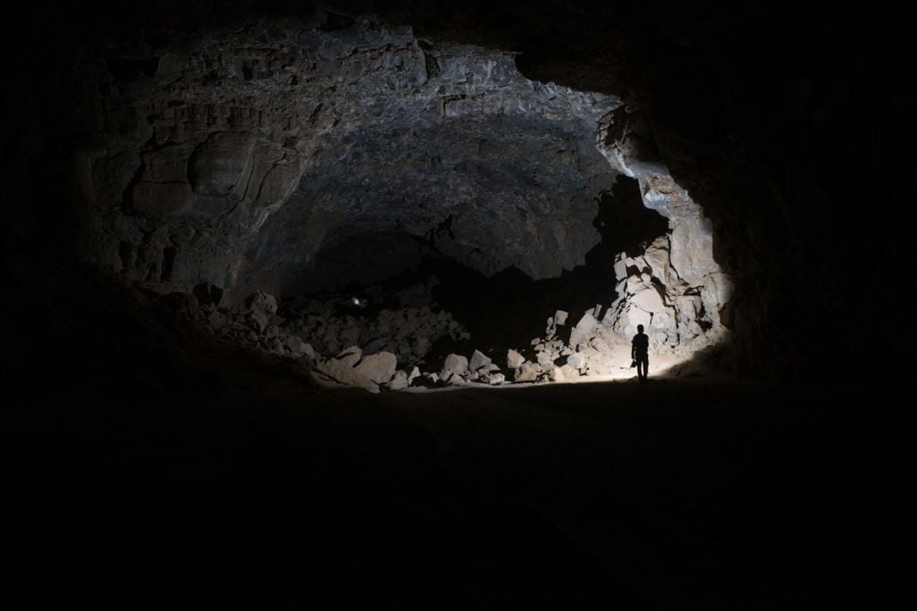 a person stands in a dimly lit cave