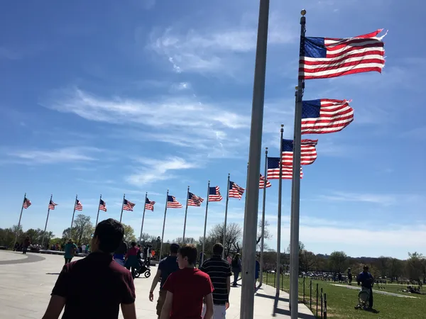 Tourists and American flags encircling the Washington Monument thumbnail