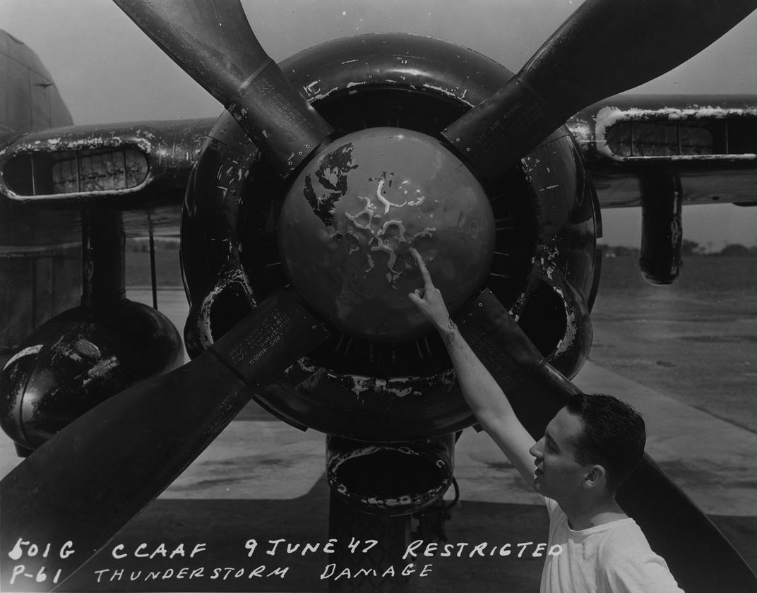A crew member points out damage to a P-61 “Black Widow” from a storm flight in June 1947.