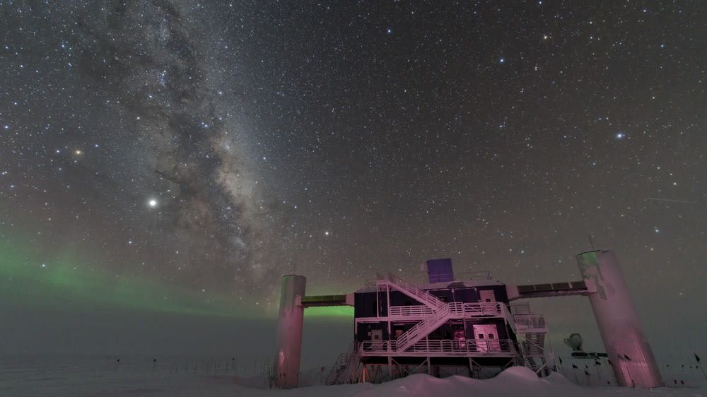 IceCube Lab with a starry night sky showing the Milky Way and faint green auroras