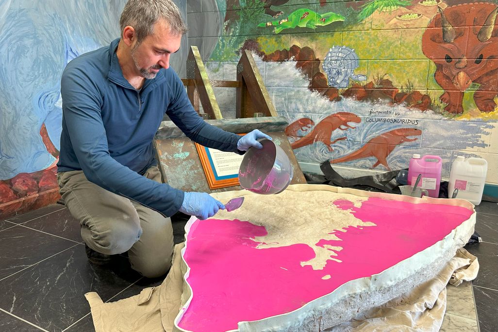 A man spreading bright pink goo on top of a rock