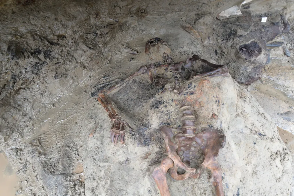 A skeleton lying half-encased in dirt and mud