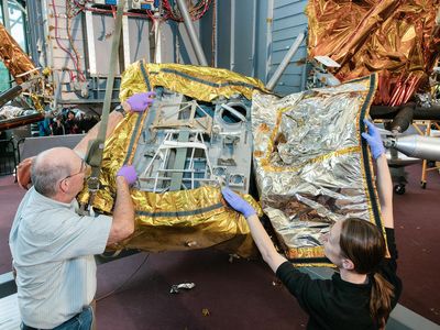 Conservators remove an original flight blanket, revealing a space for storing the supplies astronauts used to explore the lunar surface, such as cameras, geology equipment, and gear for an extended lunar stay.