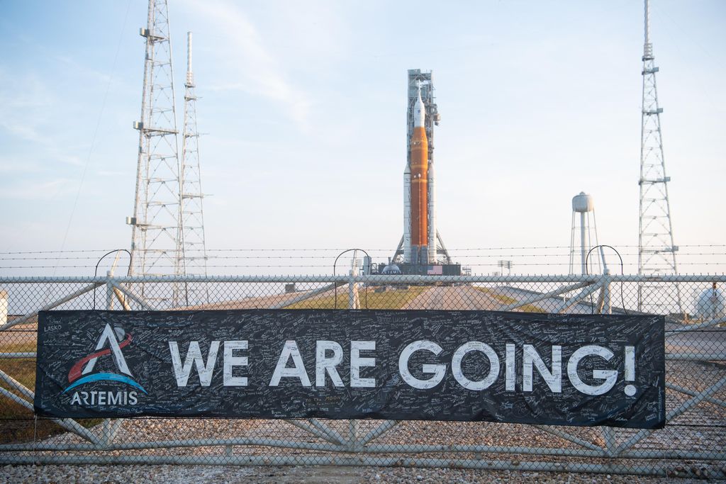 Banner on fence reads "We are going!" in front of the SLS rocket