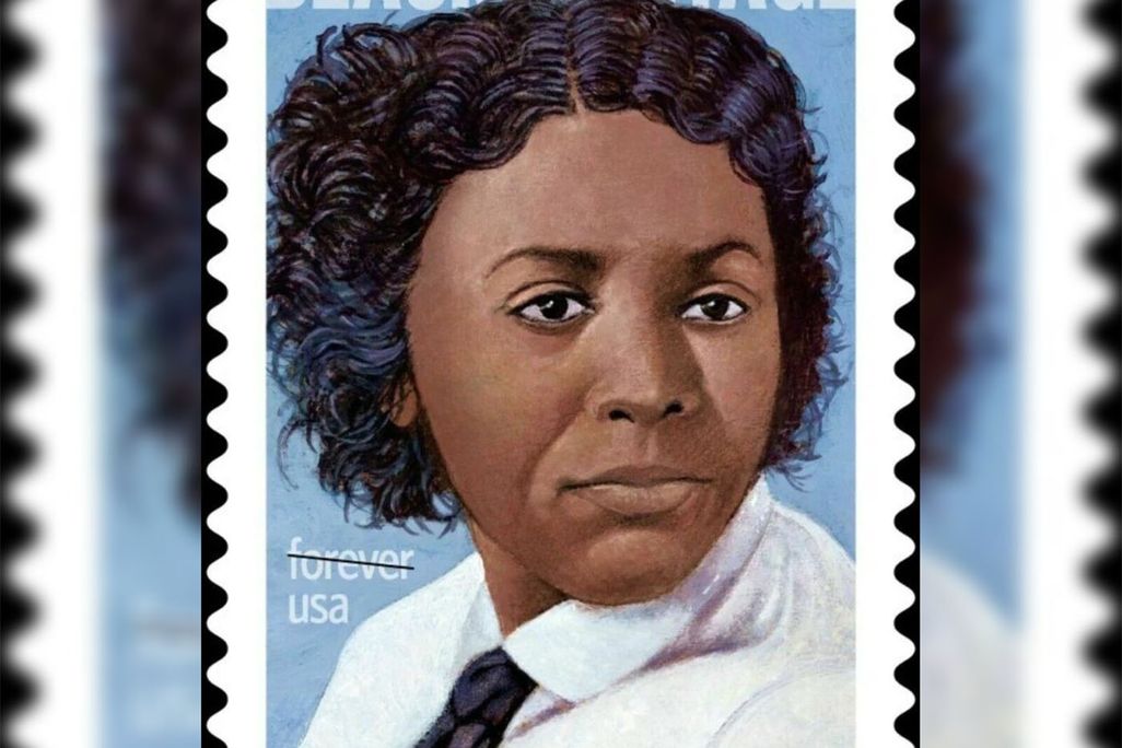 A stamp featuring a portrait of Edmonia Lewis, a Black woman with cropped wavy hair in a white shirt and black tie, on a blue background