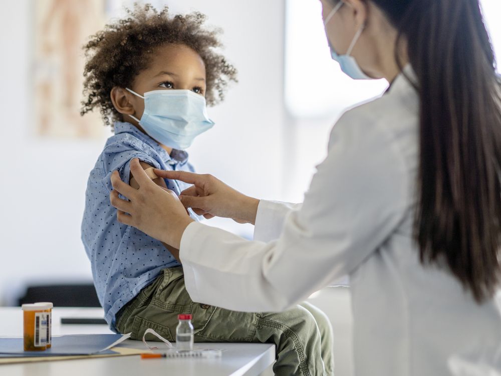 A nurse puts a band-aid on a child after he received a shot