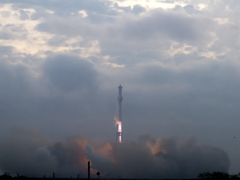 A rocket launching above a cloud of smoke into a cloudy sky