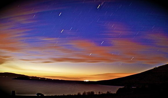 A dark sky just after dusk is set ablaze by several streaking meteorites