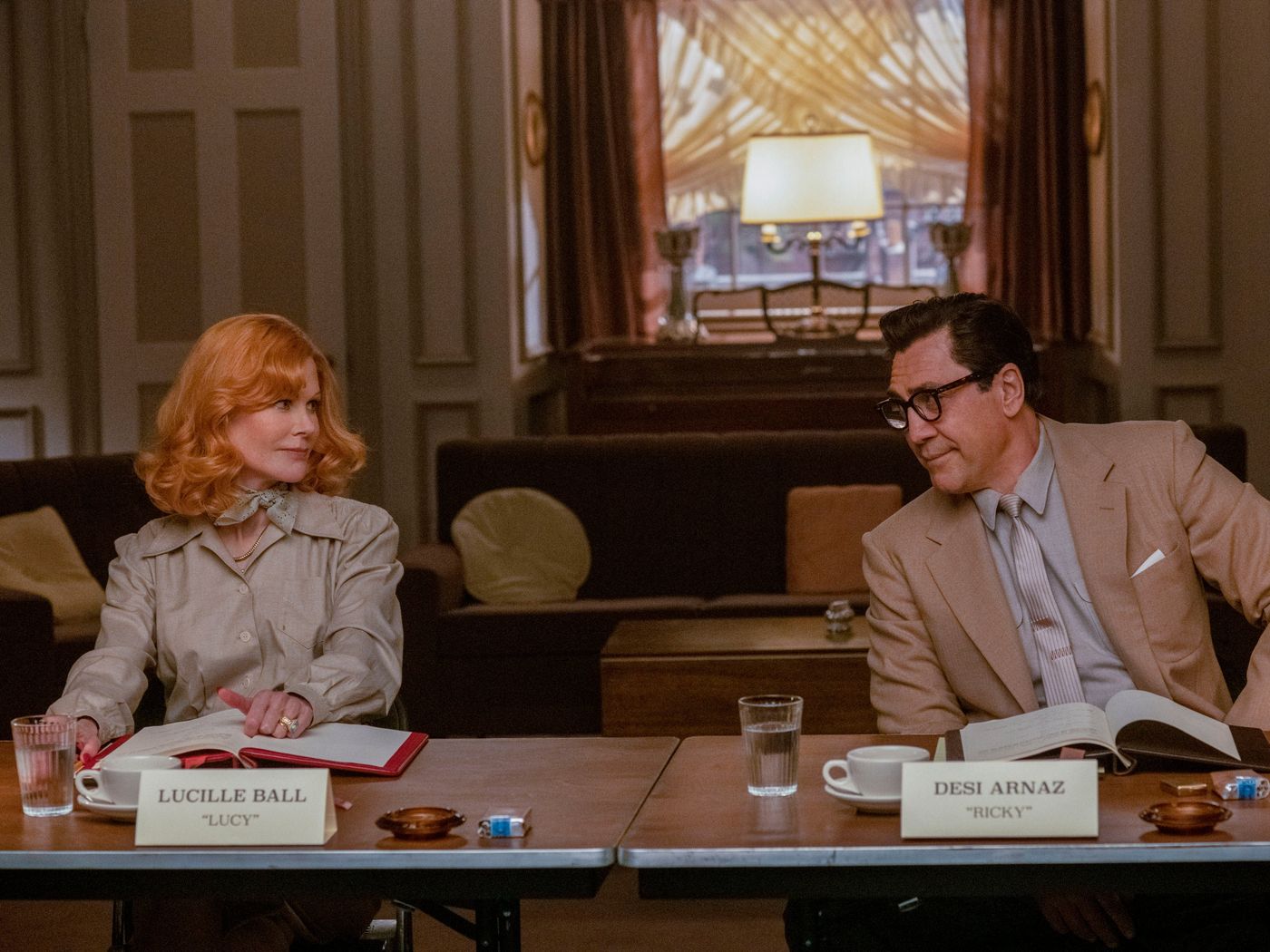Nicole Kidman as Lucille Ball and Javier Bardem as Desi Arnaz sitting at a table