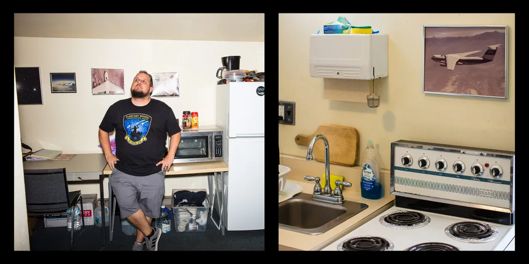 Rankin in the kitchen with his back to the counter, looking up; a view of the gas stove and small sink