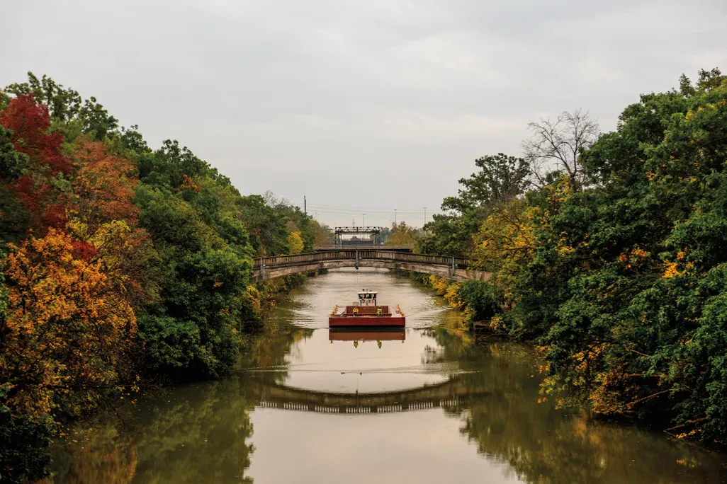 a boat in a canal going under a walking bridge