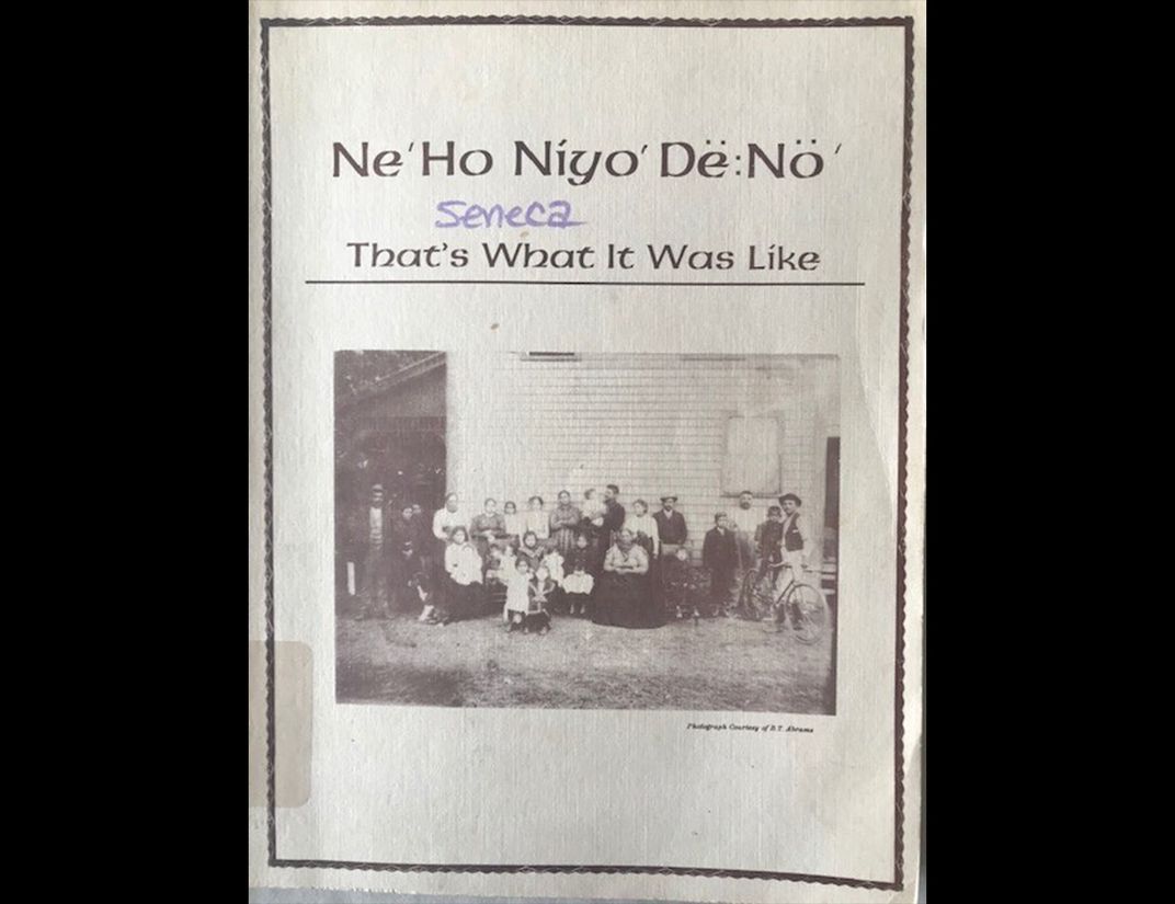 Paper cover of late 20th century publication. Printed with "Ne'Ho Niyo' Dë:Nö' , Seneca, That's What It Was like" across top third. In center is black and white photograph of group of Native Americans from early 20th century.