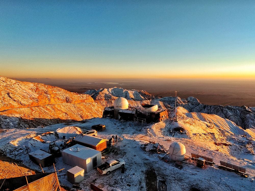 View above current construction of telescope domes on the observatory site, with blue horizon backdrop