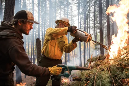 Saylor Flett, left, fans flames ignited by Jeff Greef. Air quality, weather and even bird migration affect when it&rsquo;s safe to conduct a burn.